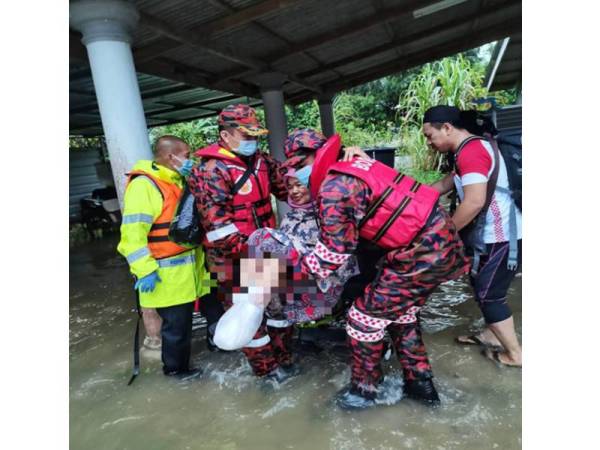 Mangsa banjir Kampung Tiong, Aini yang kudung empat jari kaki kiri didukung Ketua Balai Bomba dan Penyelamat (BBP) Pasir Tumboh, El Taraff Mohd Zachariah (dua dari kanan) bersama anggota dalam operasi pemindahan ke Pusat Permindahan Sementara (PPS) di Sekolah Kebangsaan (SK) Tiong bermula 4.22 petang hari ini.