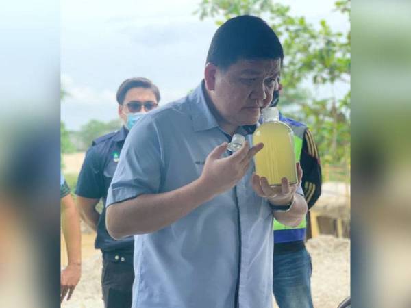 Loy Sian melihat sampel air yang menyebabkan pencemaran di Sungai Selangor pada sidang akhbar di Stesen Sementara Pemantauan Kualiti statik DI C14/C22 Sungai Selangor di Rawang semalam.