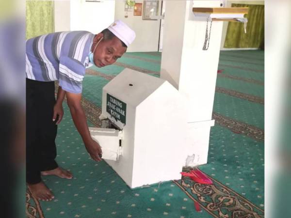 Arshad menunjukkan sebuah tabung masjid yang cuba dipecah pencuri dalam kejadian 3 Disember lalu.