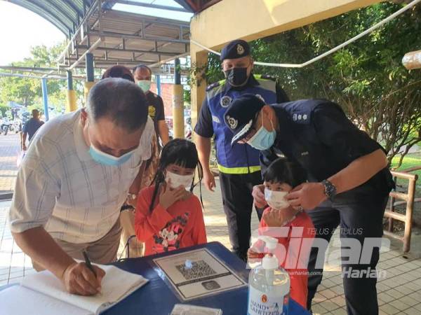 Ketua Polis Daerah Kota Setar, Asisten Komisioner Ahmad Shukri Mat Akhir (kanan) membantu seorang kanak-kanak memakai pelitup muka pada Program Konvoi Motosikal Hihg Profile Policing Ketua Polis Daerah Kota Setar di Pasar Besar Alor Setar, di sini, hari ini.