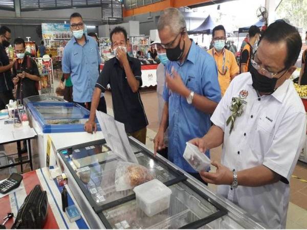 Ahmad (kanan) melihat produk sejuk beku dan telur ikan semasa meninjau barang keperluan serta bahan basah di PST Permas Jaya, Bandar Baru Permas, Johor Bahru pada Ahad.