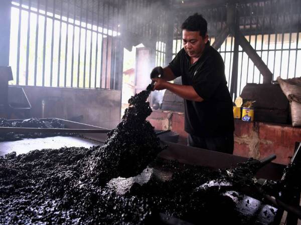 Pekerja kilang kopi Chuan Hoe, Nasir, 37, mengeluarkan kepingan kopi selepas dimasak dengan campuran gula dan marjerin sebelum dikisar untuk dijadikan serbuk ketika tinjauan di Kampung Jawa, hari ini. - Foto Bernama