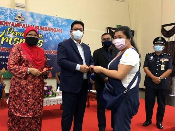 Sulaiman (dua dari kiri) menyampaikan bantuan kepada salah seorang penerima pada majlis penyampaian sumbangan sempena persediaan Hari Krismas di Seri Bendahara, Ayer Keroh hari ini.  - Foto Bernama