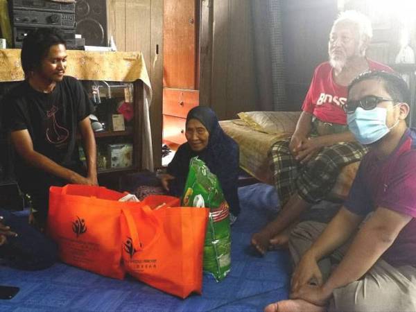 Ahmad Zhafri (kanan) menziarahi Siti Aminah dan suami serta Irfan (kiri) di rumah mereka di Kampung Peket 60, Sungai Besar, Selangor.