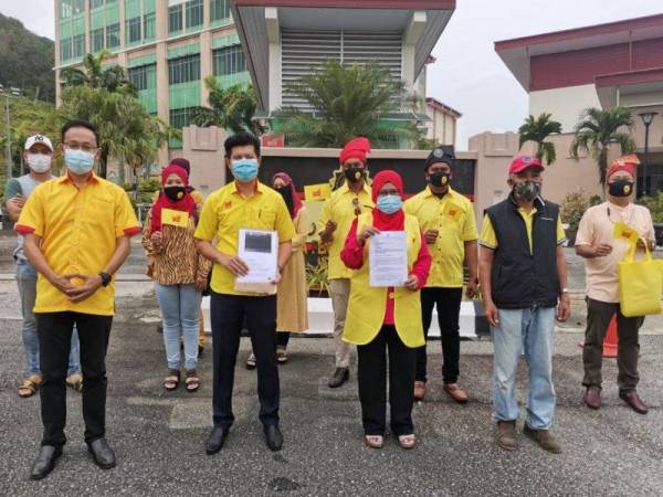 Hamidah (tengah) membuat laporan di Pejabat SPRM Meru Raya, Ipoh hari ini.