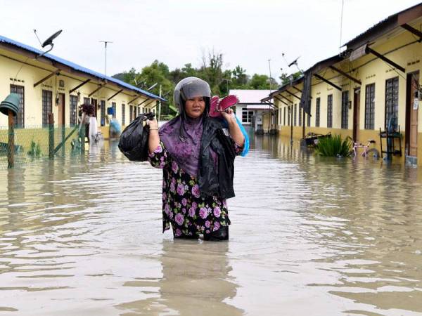 Mangsa banjir Zahiyah Yahya, 46, membawa barangan keperluan harian dengan meredah banjir untuk ke pusat pemindahan sementara (PPS) ketika tinjauan di Program Perumahan Rakyat Termiskin (PPRT) Kampung Baru Kemasik pada Sabtu. --fotoBERNAMA