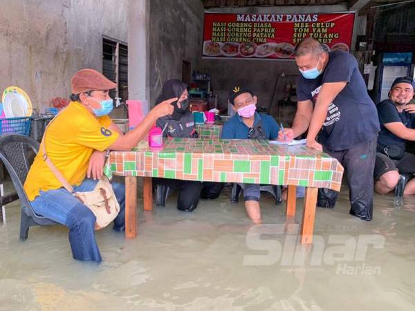 Fadhli (kanan) mengambil pesanan daripada pelanggan di kedai roti canainya di sini.