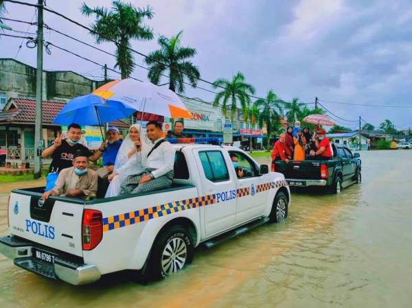 Noraishah dan Wan Mohammad Ridhwan serta keluarga mendapat bantuan daripada anggota PGA Batalion 7 Kuantan untuk mengharungi banjir ke Masjid Jubli Perak Sultan Ismail Petra, Rantau Panjang bagi menghadiri majlis akad nikah mereka pada Ahad.