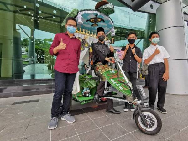 Muhammad Abidin (duduk, dua dari kiri) serta rakan sepasukan merakam gambar bersama prototaip e-beca yang dihasilkan bagi pertandingan Anugerah Inovasi Beca Terengganu 2020 yang diadakan di PSKT di Kampung Laut, Kuala Terengganu.