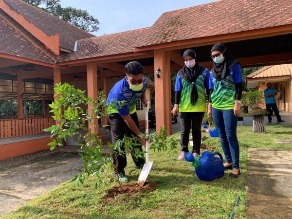 Muhamad Syafiq (kiri) melakukan gimik penanaman pokok di Taman Eko-Rimba Bukit Bakar pada Selasa.