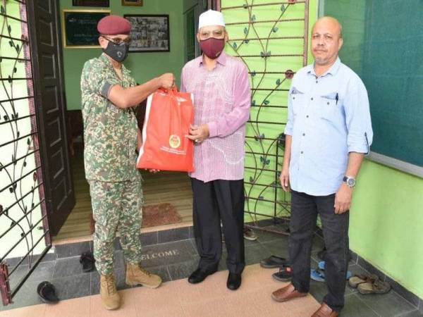 Shairul Amin (kiri) mewakili Sultan Muhammad V menyerahkan pek sumbangan mangsa banjir kepada Ahmad di Tumpat pada Khamis