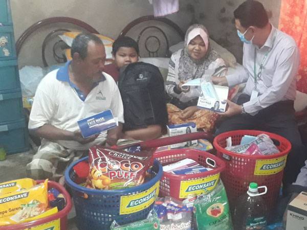 Zamzuri (dua dari kanan) menunjukkan pelitup muka kepada Sarina ketika ditemui di rumah mereka di Lorong Masjid Batu 3, Tandop pada Rabu. Turut kelihatan Jaafar (kiri) dan Muhammad Iman Nabihan (dua dari kiri).