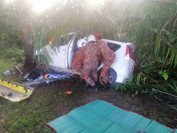 Anggota bomba mengeluarkan mayat dua beranak yang tersepit selepas Perodua Alza dipandu terbabas mangsa dan melanggar sebatang pokok di Jalan Felda Bukit Batu, Kulai pada Ahad.