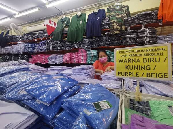 Kit Mei menyusun baju sekolah yang dijual di kedainya di Seremban.