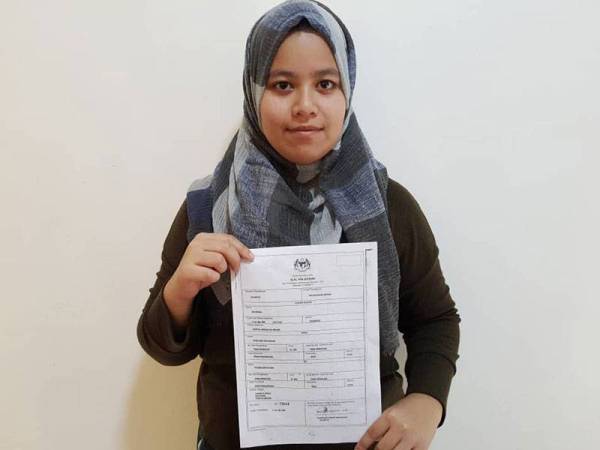 Nik Munira Mohd Sabri menunjukkan surat beranak beliau di Meru, Klang pada Rabu.