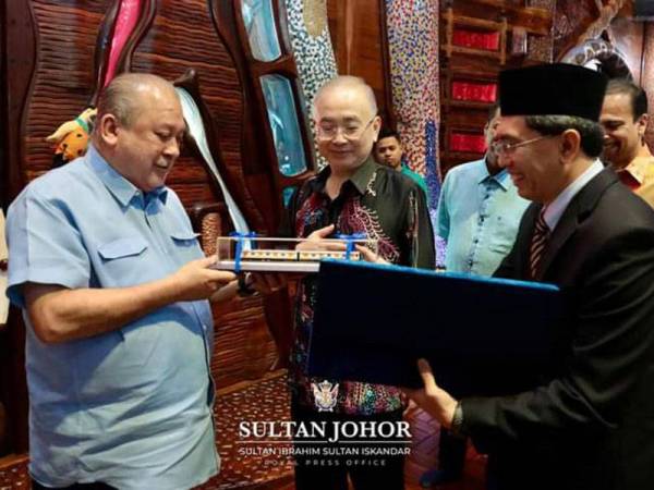 Sultan Ibrahim menerima cenderamata daripada Mohd Zarif dengan diperhatikan Ka Siong selepas mempersembahkan kepada baginda laporan terkini projek RTS Link di Istana Flintstones, Mersing pada Rabu. - Foto Facebook rasmi Sultan Ibrahim Sultan Iskandar