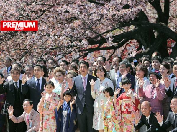 Bekas Perdana Menteri Jepun, Shinzo Abe (berdiri tengah) dan para tetamu bergambar di bawah pokok sakura di Tokyo pada tahun lalu. - Foto AFP