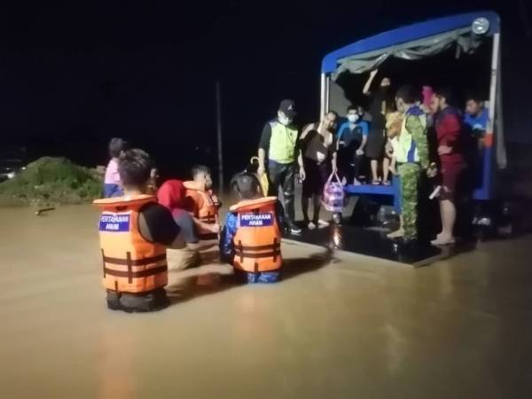 Anggota Jabatan Pertahanan Awam Malaysia memindahkan penduduk yang terjejas akibat banjir di Kampung Kangar Tebrau, Johor Bahru pada malam Sabtu.