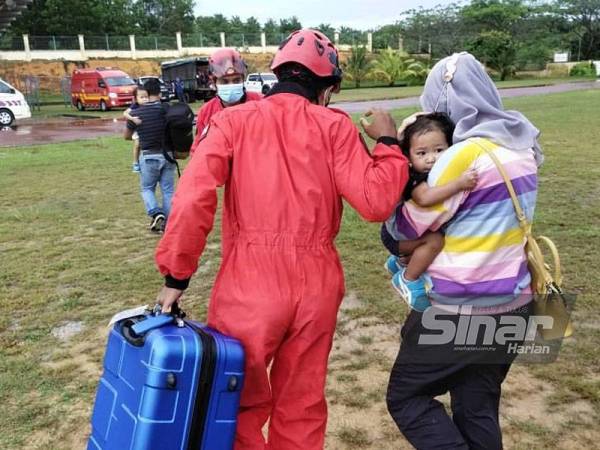 Anggota bomba memindahkan seorang wanita yang sarat mengandung dengan menggunakan helikopter dari Ladang Sungai Tawing ke SM Sains Sembrong, Kluang pada Ahad.