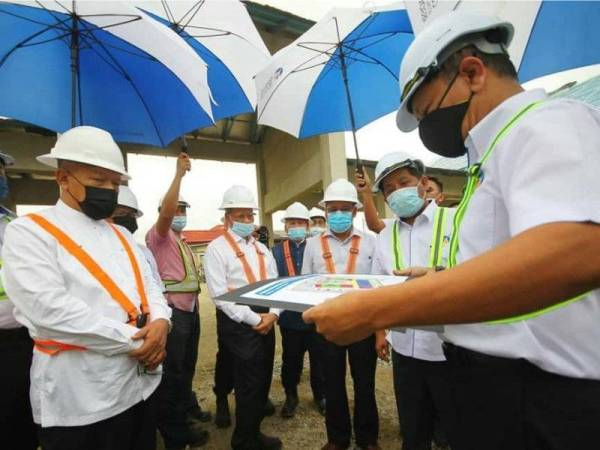 Mustapa (empat dari kanan) bersama Ahmad (kiri) dan Che Abdullah (tiga dari kanan) mendengar taklimat berkaitan projek pembangunan Kampung Laut, Tumpat pada Ahad.