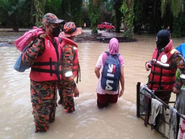 Anggota JBPM Teluk Intan membantu memindahkan mangsa banjir di Kampung SC Ayer Hitam pada Ahad.