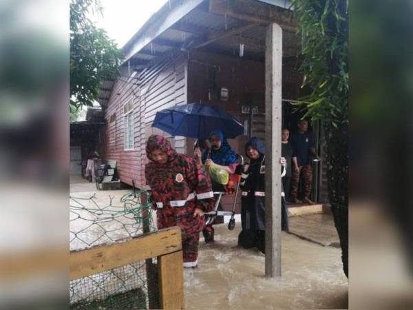 Anggota bomba membantu memindahkan mangsa banjir di Kampung Rumpia, Beserah yang terjejas banjir.