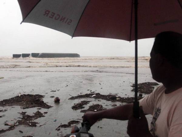 Seorang penduduk Roslan Abdullah, 51 melihat tongkang yang terbalik di Pantai Kampung Baru Beserah, Kuantan, pada Ahad. Menurut Roslan tongkang hanyut itu disedari terdampar 1 Januari lalu akibat laut bergelora dan dihanyutkan ombak kuat. - Foto Bernama