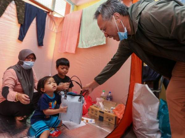 Hasni beramah mesra dengan keluarga mangsa banjir semasa mengadakan tinjauan di pusat pemindahan sementara (PPS) di Sekolah Kebangsaan Laksamana, Kota Tinggi pada Isnin.