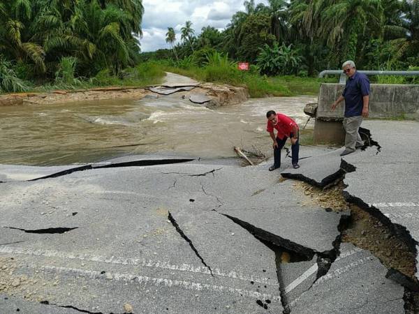 Zainol Fadzi (kiri) melihat struktur Jalan Besar Chikus menghubungkan Attaduri dan Chikus yang rebak akibat limpahan air Sungai Batang Padang pada Selasa.
