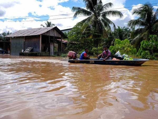 Beberapa penduduk menggunakan bot meredah banjir untuk mendapatkan bekalan makanan dan keperluan harian ketika tinjauan di sekitar kawasan Paya Garok, Jerantot, hari ini. - Foto Bernama