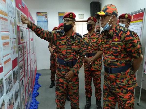 Muhammad Hamdan (kanan) mendengar taklimat operasi banjir di Balai Bomba dan Penyelamat Kota Tinggi pada Khamis.