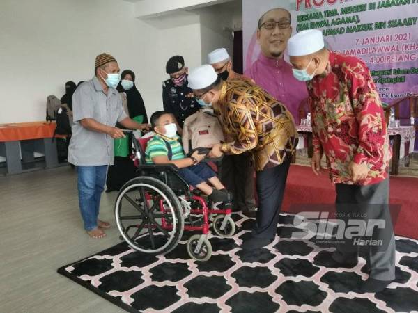 Ahmad Marzuk (dua dari kanan) menyampaikan bantuan persekolahan kepada penerima pada Program Kembali Ke Sekolah di Sekolah Rendah Integrasi Islam Darul Ulum di Bandar Springhill, Port Dickson pada Khamis.