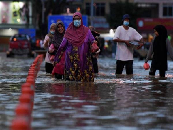 Sebuah keluarga meredah banjir untuk ke pusat pemindahan sementara selepas rumah mereka dilanda banjir ketika tinjauan di bandar Chukai hari ini. - Foto Bernama