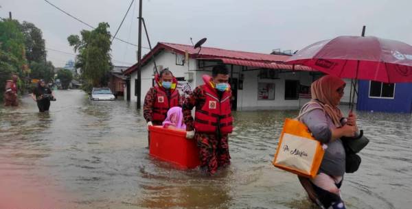 Anggota bomba membantu penduduk yang terjejas akibat banjir di Kampung Sri Jaya, Kota Tinggi.