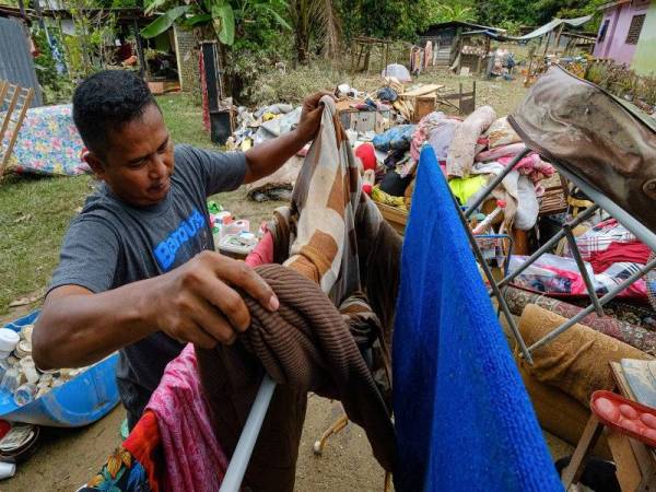 Mangsa banjir, Khairul Fazli, 44, kelihatan menjemur cadar ketika melakukan kerja-kerja pembersihan di rumahnya yang dilanda banjir di Kampung Balun Slim River, Khamis. Foto Bernama