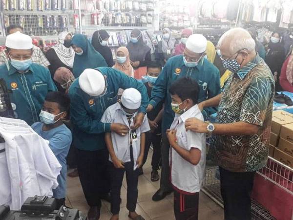 Mahdzir (kanan) membantu salah seorang pelajar mencuba pakaian sekolah pada Program Sumbangan Pakaian Sekolah Oleh Yayasan Kemiskinan Darul Aman (Yaked) di Kuala Nerang pada Sabtu.