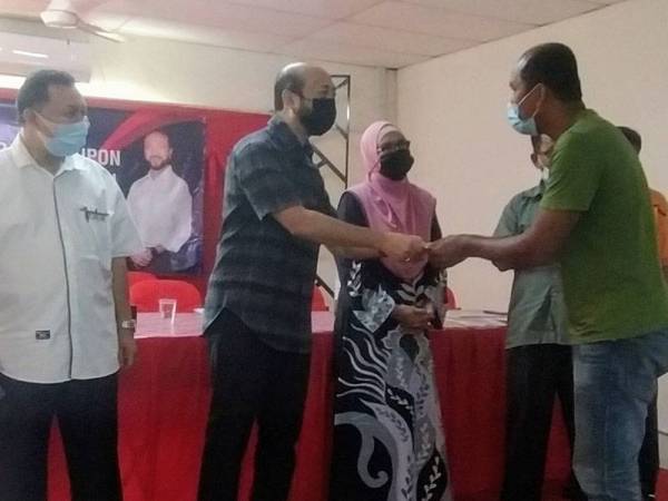 Mukhriz (dua dari kiri) menyerahkan kupon kepada waris penerima pada Majlis Penyerahan Kupon Bantuan Pakaian Sekolah sempena Program Back To School Parlimen Jerlun di Pusat Khidmat Parlimen Jerlun pada Sabtu.