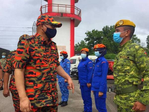 Mohammad Hamdan (kiri) beramah mesra dengan petugas banjir ketika turun padang meninjau situasi banjir di Rantau Panjang.