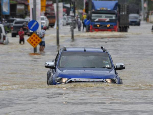 Sebuah kenderaan pacuan empat roda kelihatan meredah air banjir untuk ke pekan berikutan sebahagian jalan untuk ke Rantau Panjang telah ditenggelami air pada Khamis. - Foto Bernama