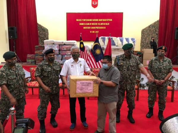 Ismail Sabri (tiga dari kiri) menyampaikan sumbangan kepada Akbar untuk disampaikan kepada mangsa banjir di Majlis Penyerahan Barang Bantuan Kepada Mangsa Banjir Negeri Kelantan oleh Menteri Kanan Pertahanan di Kem Pengkalan Chepa pada Ahad.
