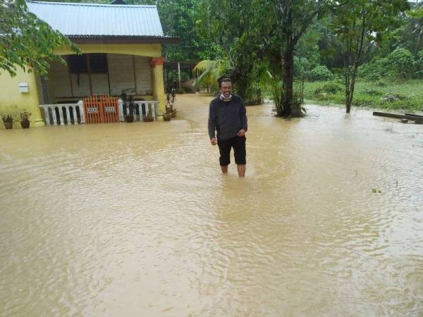 Rahim meninjau keadaan sekitar rumah yang mula dinaiki air di Kampung Kelantan, Kota Tinggi pada pagi Ahad.