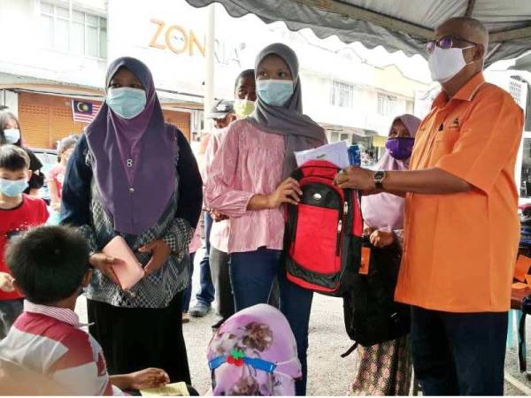 Mahfuz (kanan) menyerahkan sumbangan pakaian dan beg sekolah kepada penerima bawah DUN Bukit Pinang, Derga serta Bukit Lada meliputi lebih 400 pelajar sekolah.