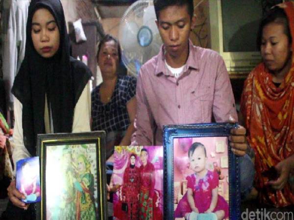 Sri (kiri) menunjukkan gambar kedua ibu bapa termasuk adiknya yang merupakan penumpang pesawat Boeing 737-500 Sriwijaya Air yang terhempas di perairan Kepulauan Seribu, Jakarta pada Sabtu lalu. - Foto Detik.com