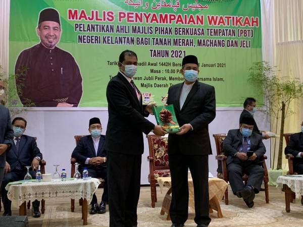 Dr Izani (kanan) menyampaikan watikah pelantikan Ahli Majlis Pihak Berkuasa Tempatan (PBT) Negeri Kelantan bagi kawasan Tanah Merah, Jeli dan Machang di Dewan Majlis Daerah Tanah Merah di Tanah Merah pada Isnin.