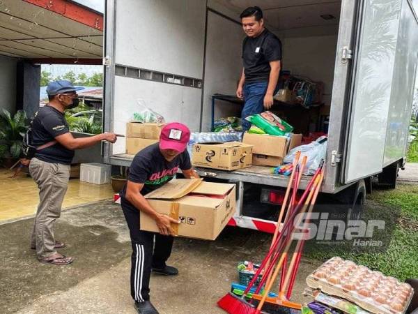 Shahrul( tengah) ketika mengagihkan barangan milik mangsa banjir di Kampung Batu Kapor, Mentakab di sini