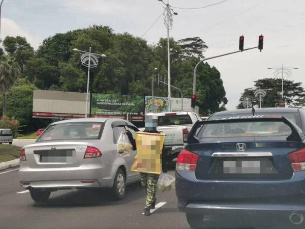 Seorang wanita sedang berniaga jeruk mangga di persimpangan lampu isyarat.