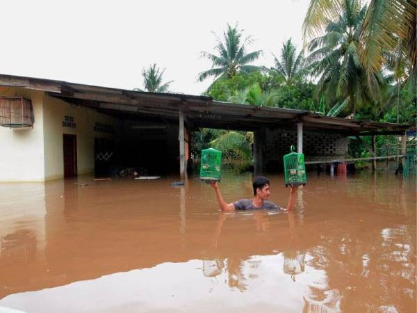 Mohd Azrie Danial Nazri, 21 menyelamatkan burung peliharaan setelah rumahnya ditenggelami banjir di Kampung Semangat semalam. Foto Bernama