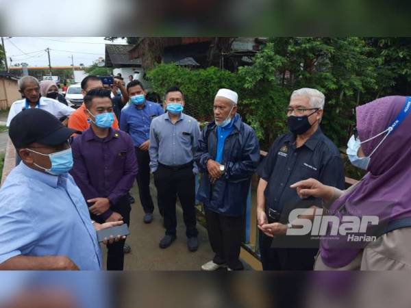 Hassan (dua dari kanan) mendengar permasalahan dan perkembangan banjir semasa melawat dan menyampaikan sumbangan kepada mangsa banjir di Kampung Masjid, Pasir gudang pada Selasa.