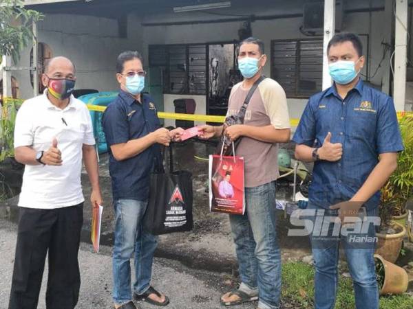 Mohd Fasiah (dua dari kiri) menyampaikan sumbangan dan bantuan kewangan kepada Mohd Rizal (dua dari kanan) selepas rumah teres disewa terbakar pada malam Selasa.