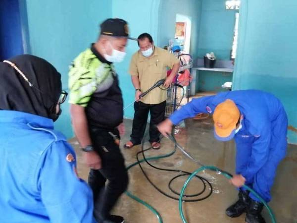 Rosleli dan anggota APM membantu mangsa banjir membersihkan rumah yang kotor dengan tanah dan lumpur di Kampung Tembioh, Kota Tinggi, pada Khamis.